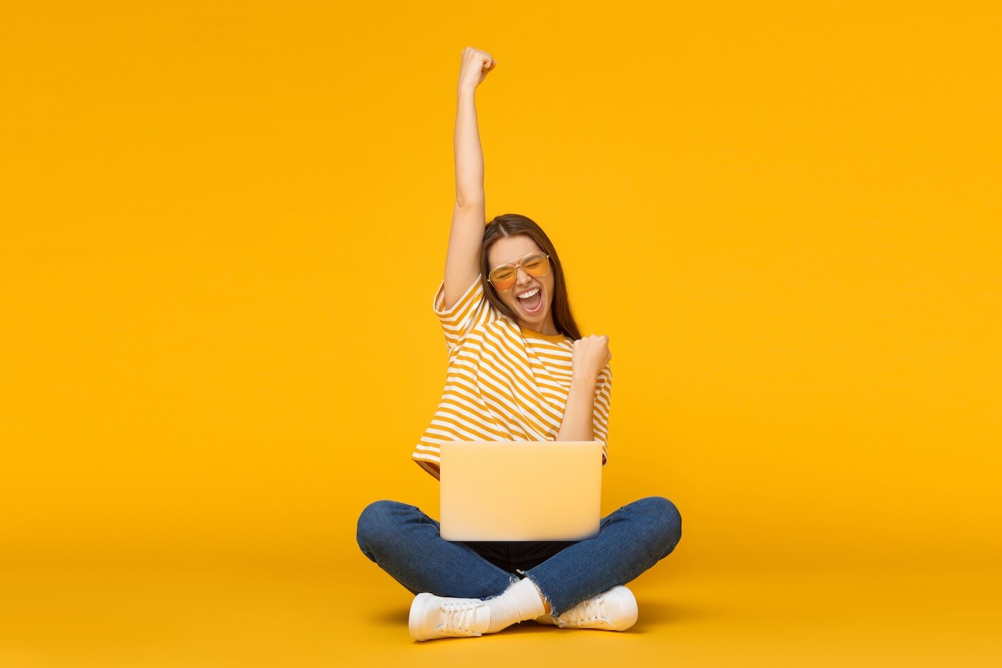 Woman sitting with laptop raising her arm in triumph