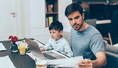 Remote worker working at kitchen table accompanied by toddler 
