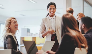 Group of professionals talking and laughing around the office