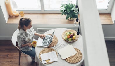 Woman working from home with cup of tea and laptop