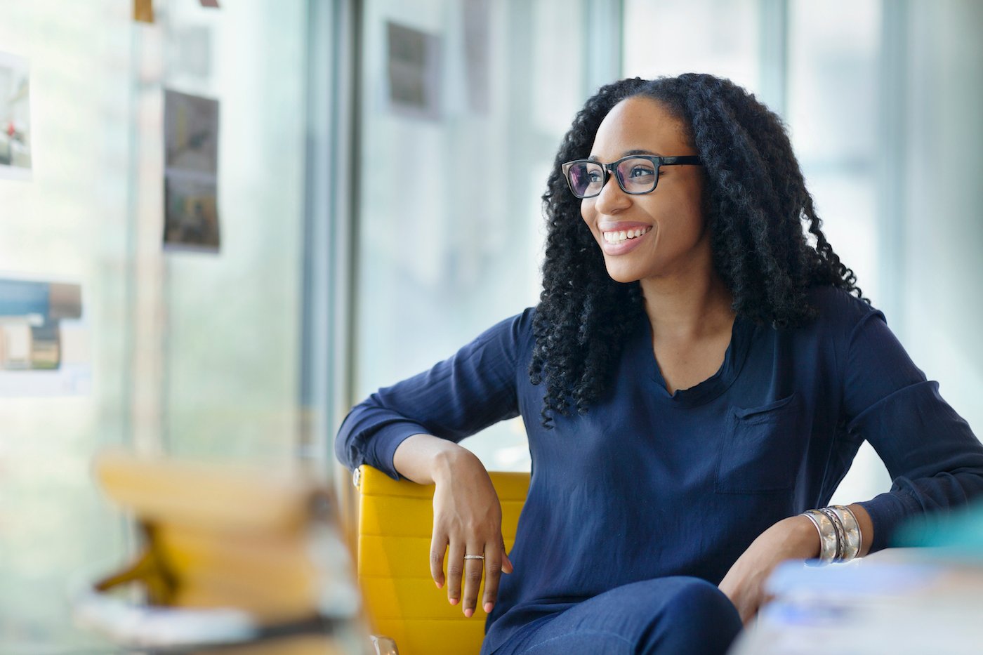 Woman at desk smiling over her shoulder at #GoToGetsIT research about improving the relationship between employees and IT departments