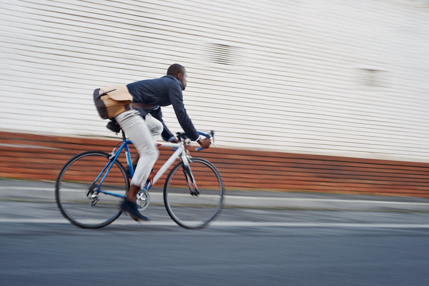 Young business man in casual work clothes riding bicycle, representing navigating economic uncertainty for SMBs and IT managers