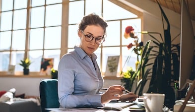 Woman working from home office with desktop and large window