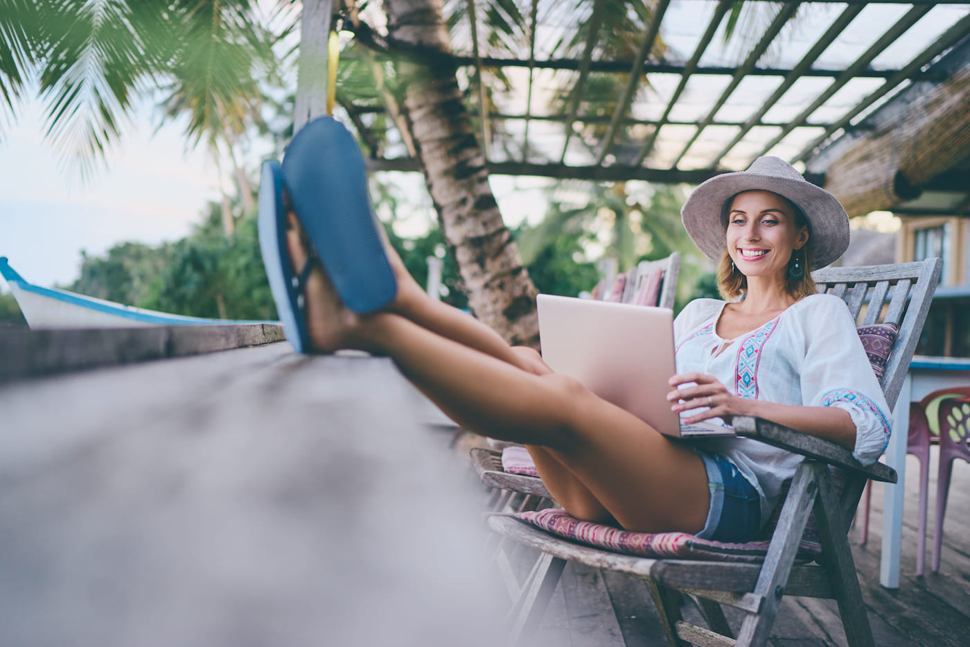 Woman Virtual Volunteering from an outdoor patio in the tropics with her feet up and laptop open